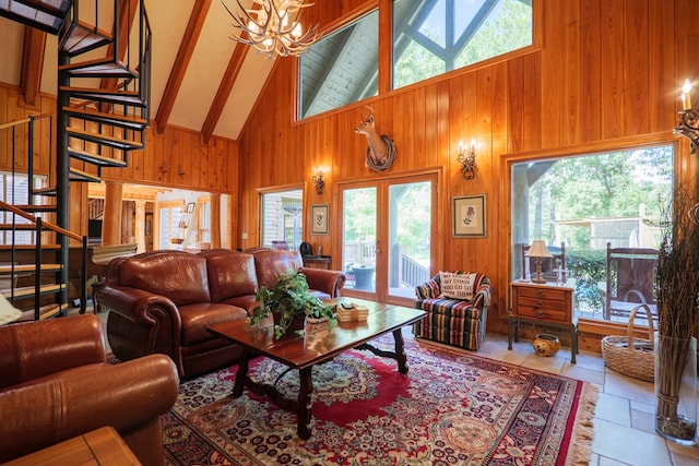 living room with wooden walls, plenty of natural light, high vaulted ceiling, and a chandelier