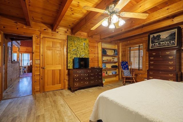 bedroom with ceiling fan, beam ceiling, wooden walls, and light hardwood / wood-style flooring