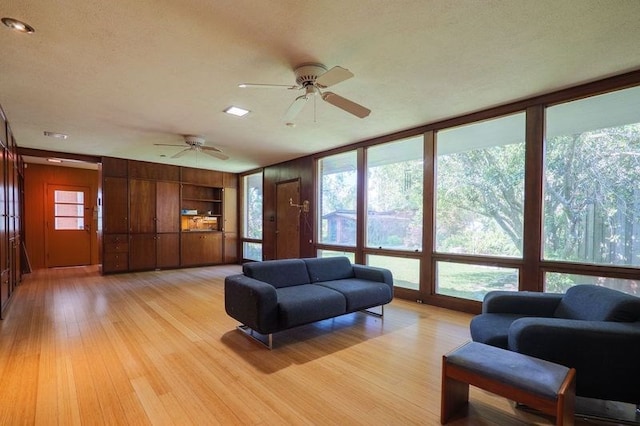1614 N Patterson St, Valdosta, GA 31602 - living room with wood walls, ceiling fan, light wood-type flooring, and plenty of natural light