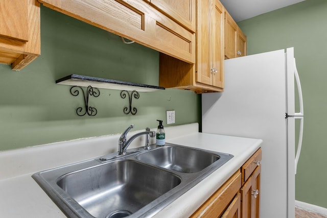 kitchen with light countertops, freestanding refrigerator, and a sink