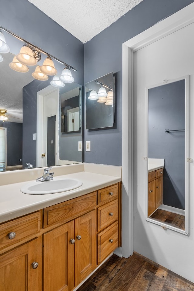bathroom with wood finished floors, vanity, and a textured ceiling