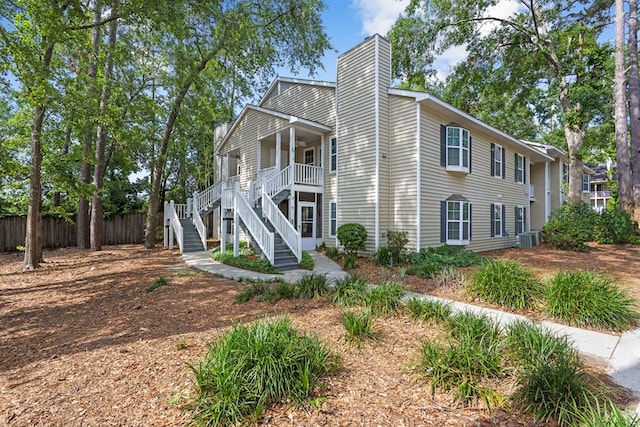 view of side of property featuring stairway, a chimney, fence, cooling unit, and a porch