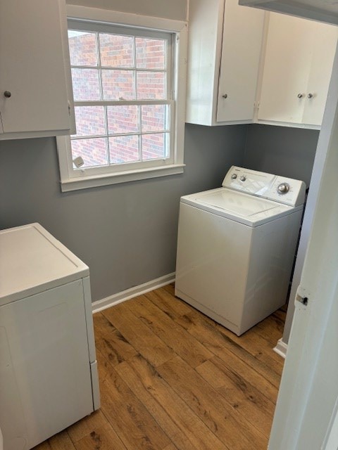 clothes washing area featuring baseboards, cabinet space, washer / clothes dryer, and light wood finished floors