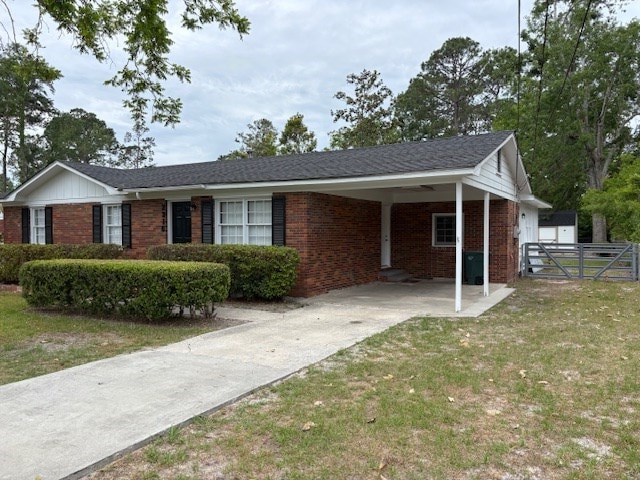 view of home's exterior featuring brick siding, driveway, fence, and an attached carport
