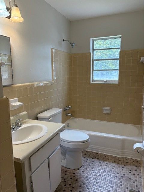 full bath with vanity, toilet, a wainscoted wall, tile walls, and  shower combination