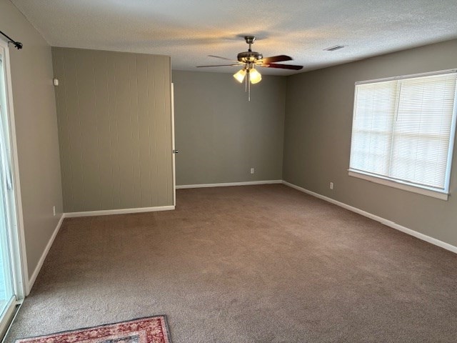 unfurnished room with plenty of natural light, baseboards, ceiling fan, and carpet flooring