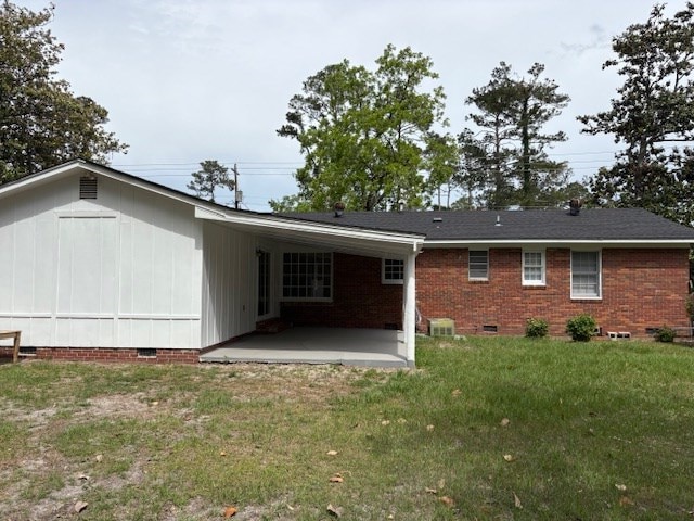 rear view of house featuring a patio, a lawn, and crawl space