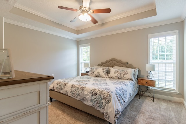 carpeted bedroom with multiple windows, a tray ceiling, and ceiling fan