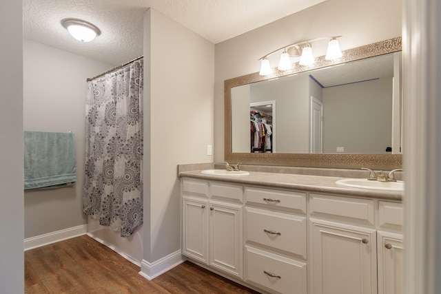 bathroom with hardwood / wood-style floors, vanity, shower / bath combination with curtain, and a textured ceiling