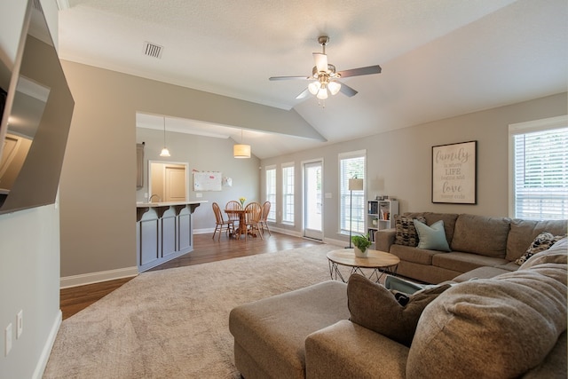 living room with dark hardwood / wood-style floors, vaulted ceiling, plenty of natural light, and ceiling fan