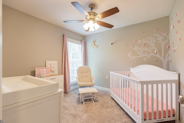 bedroom featuring a textured ceiling, ceiling fan, light carpet, and a nursery area