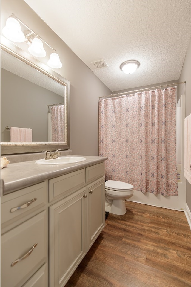 full bathroom featuring shower / bath combo, wood-type flooring, a textured ceiling, toilet, and vanity