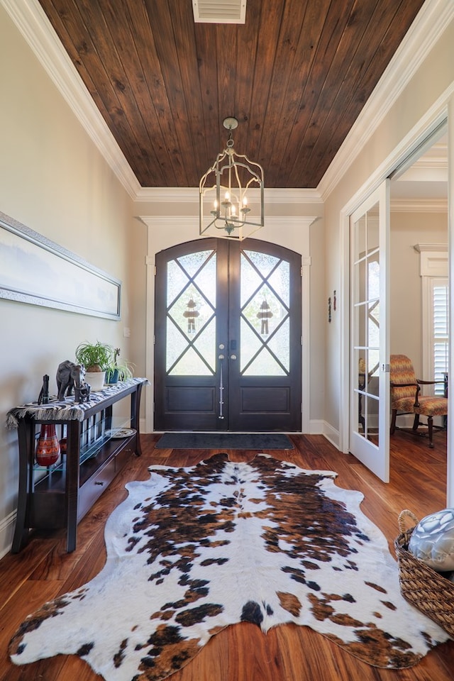 foyer with dark hardwood / wood-style flooring, crown molding, a wealth of natural light, and french doors