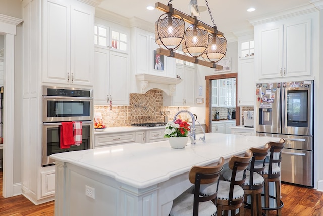 kitchen with appliances with stainless steel finishes, white cabinetry, and a kitchen island with sink