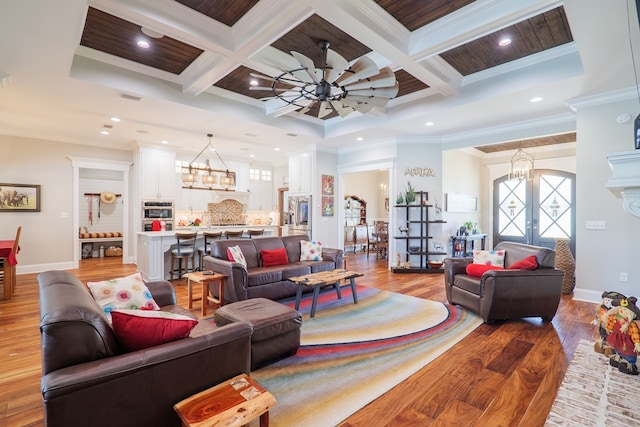 living room featuring light hardwood / wood-style flooring, coffered ceiling, and ornamental molding