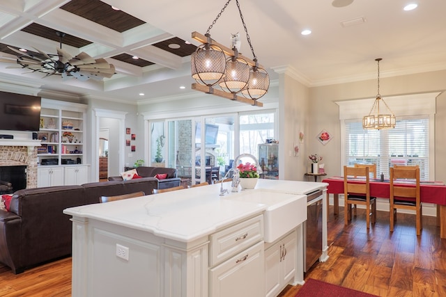 kitchen with a wealth of natural light, coffered ceiling, pendant lighting, a center island with sink, and hardwood / wood-style floors