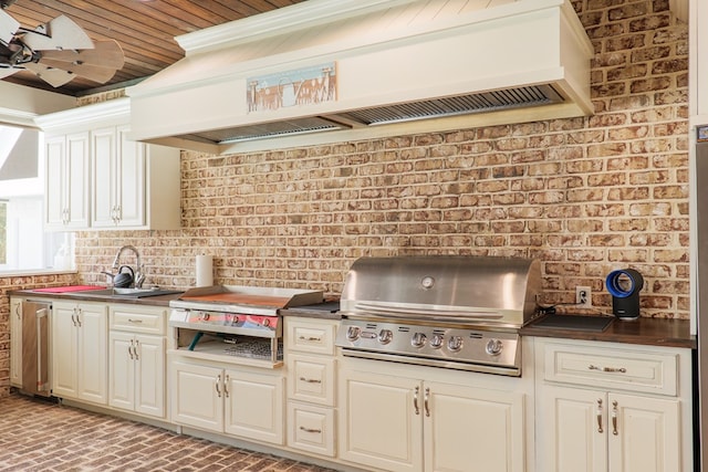 kitchen with custom exhaust hood, sink, and brick wall