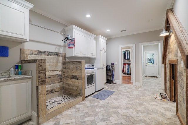 kitchen featuring light stone countertops, white cabinetry, washer and clothes dryer, and ornamental molding