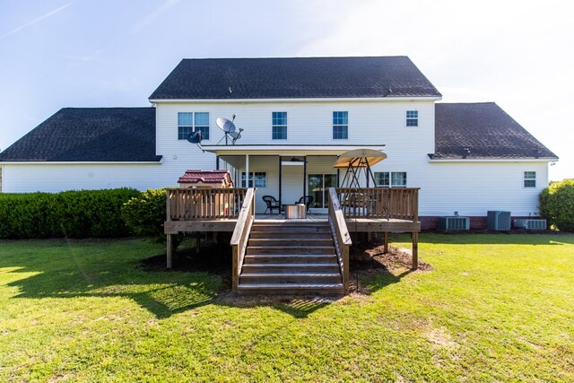 rear view of property with a yard, a wooden deck, and central AC