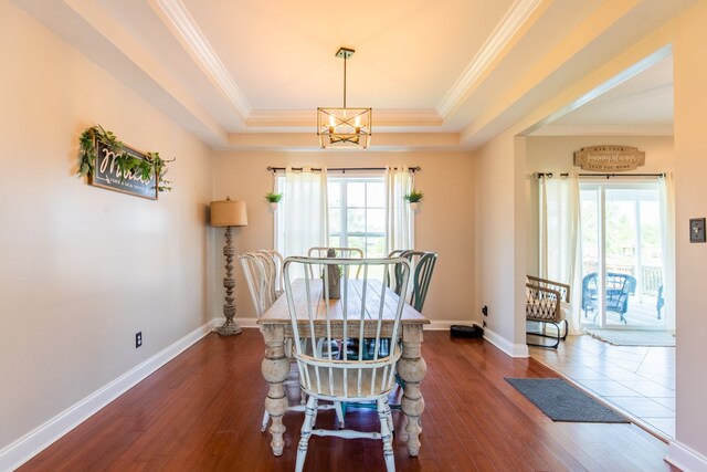 dining room with a tray ceiling, a notable chandelier, dark hardwood / wood-style floors, and ornamental molding