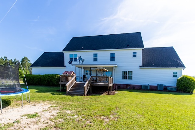 back of house with central air condition unit, a trampoline, a lawn, and a wooden deck