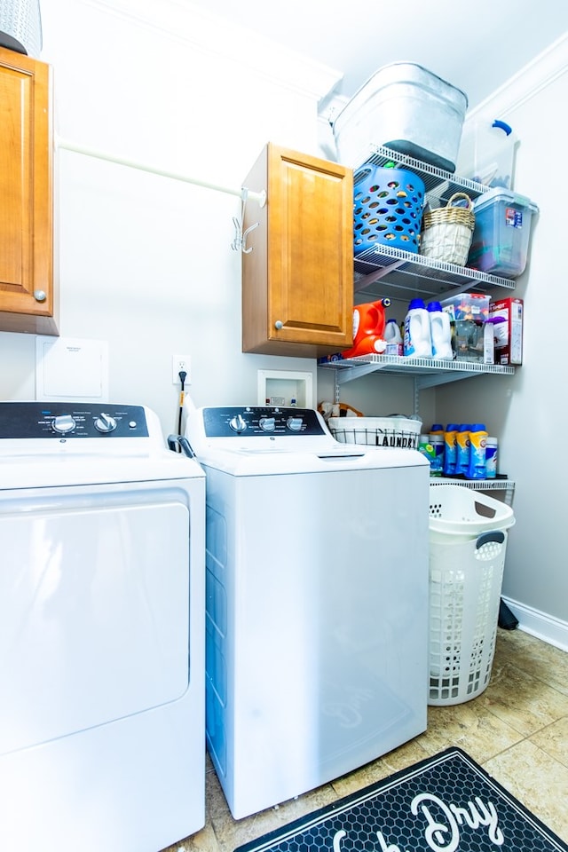 washroom featuring cabinets, ornamental molding, and washing machine and clothes dryer