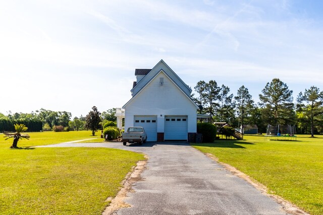 exterior space with a trampoline, a garage, and a lawn