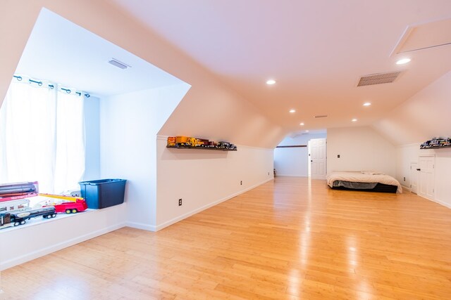 additional living space featuring light wood-type flooring and vaulted ceiling