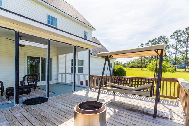 wooden deck with a yard and an outdoor fire pit