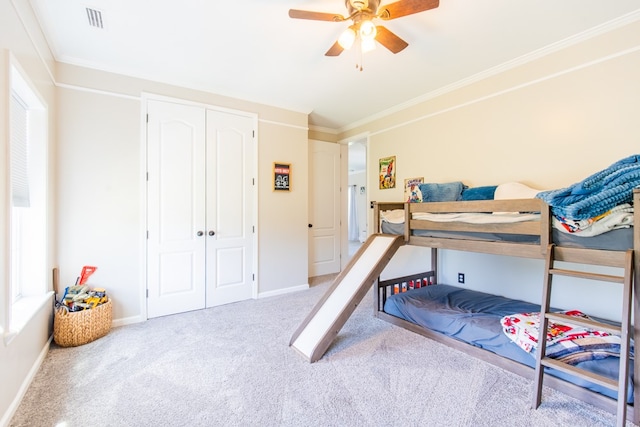 carpeted bedroom with ceiling fan, a closet, and ornamental molding