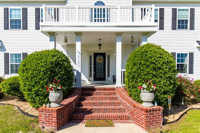 entrance to property featuring covered porch and a balcony