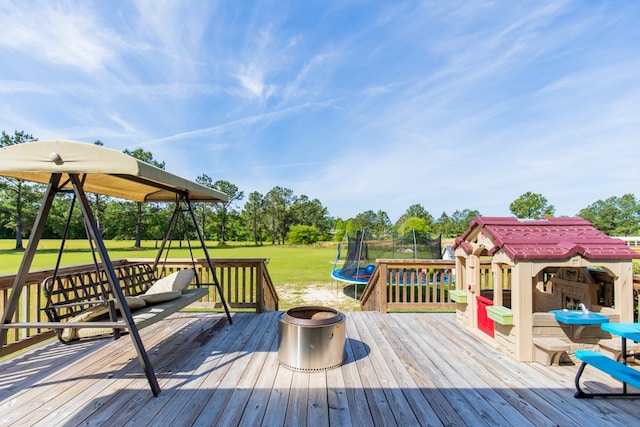 wooden deck with a playground, a trampoline, and a lawn