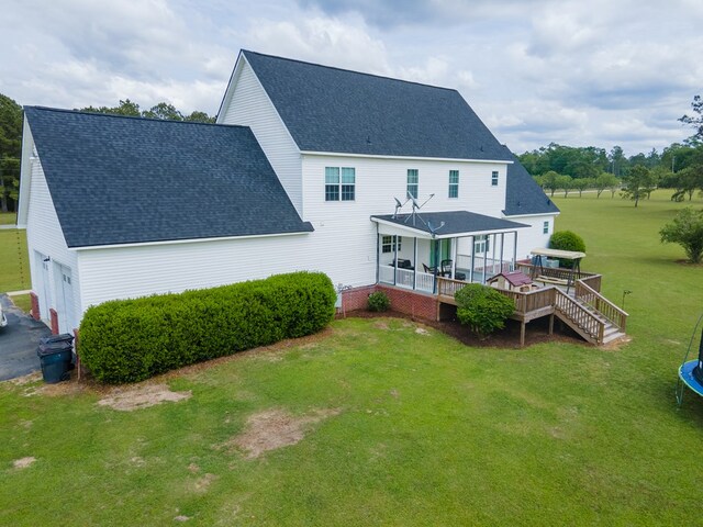 rear view of property featuring a lawn, a porch, and a trampoline