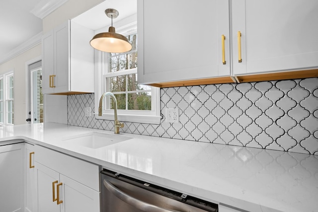 kitchen with pendant lighting, crown molding, stainless steel dishwasher, white cabinets, and a sink