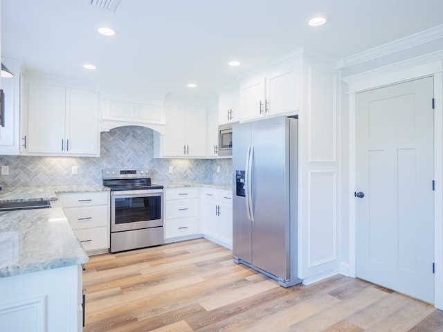 5674 Clydetta Dr, Lake Park, GA 31636 - kitchen with appliances with stainless steel finishes, premium range hood, light wood-style floors, white cabinets, and ornamental molding