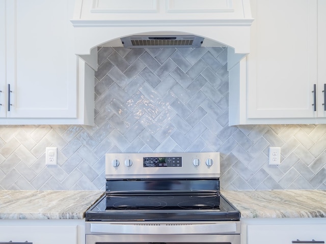 5674 Clydetta Dr, Lake Park, GA 31636 - kitchen view of stainless steel range with electric stovetop, backsplash, white cabinetry, and light stone countertops