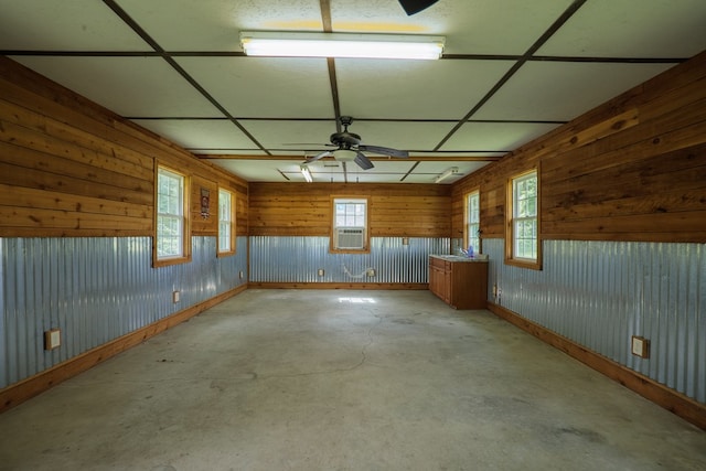 empty room featuring ceiling fan, wood walls, and cooling unit