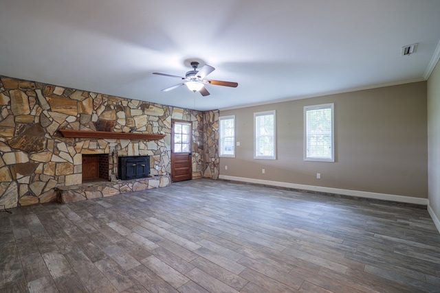 unfurnished living room featuring dark wood-type flooring, a stone fireplace, and ornamental molding