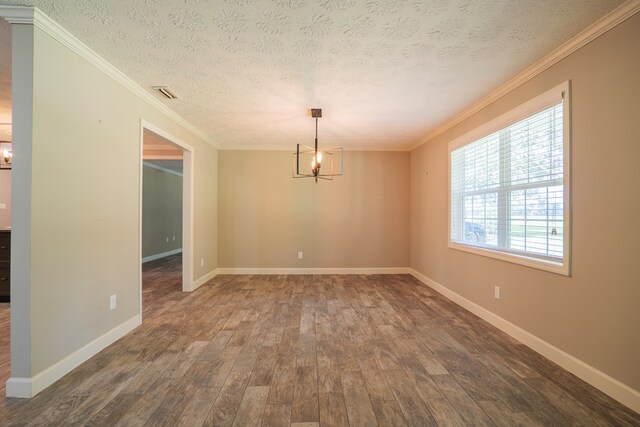 empty room with a chandelier, ornamental molding, a textured ceiling, and dark wood-type flooring