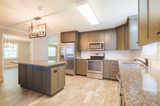 kitchen featuring dark stone countertops, sink, decorative light fixtures, and appliances with stainless steel finishes