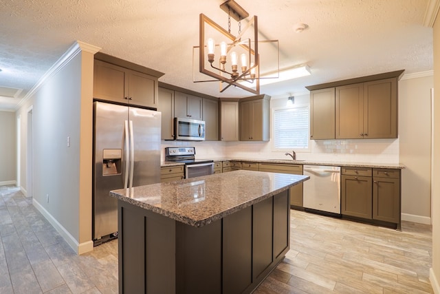 kitchen with appliances with stainless steel finishes, light hardwood / wood-style flooring, hanging light fixtures, and ornamental molding