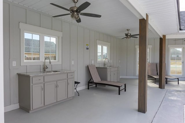 interior space with light stone countertops, sink, and ceiling fan