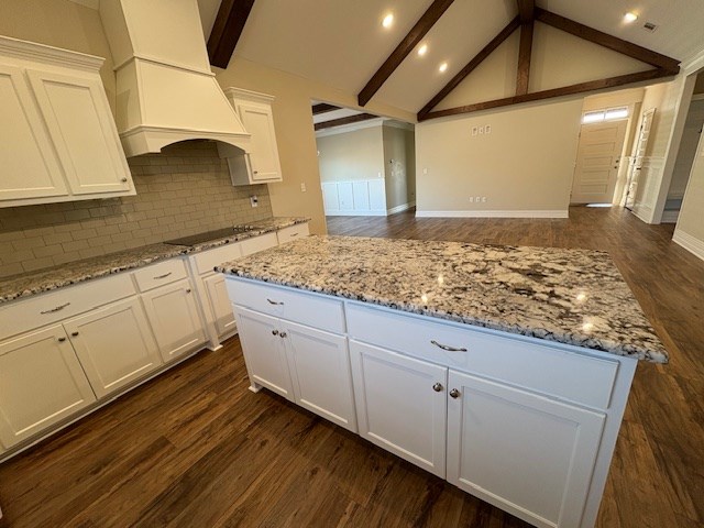 kitchen with white cabinetry, black electric cooktop, custom range hood, and a kitchen island