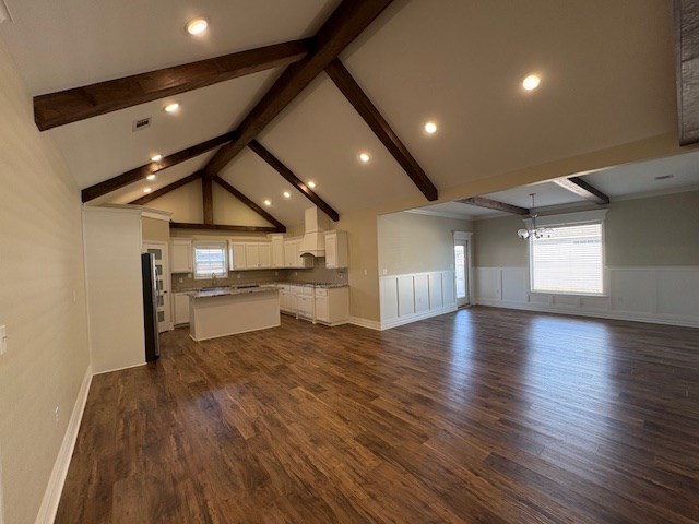 unfurnished living room featuring dark hardwood / wood-style floors, beam ceiling, a chandelier, and high vaulted ceiling