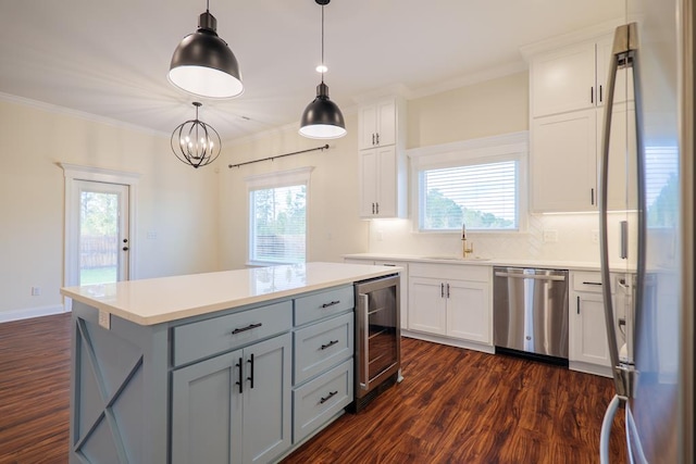 kitchen featuring dark wood-style flooring, appliances with stainless steel finishes, ornamental molding, a sink, and beverage cooler