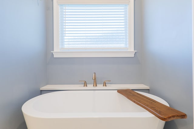 bathroom featuring a sink, a freestanding tub, and a wealth of natural light