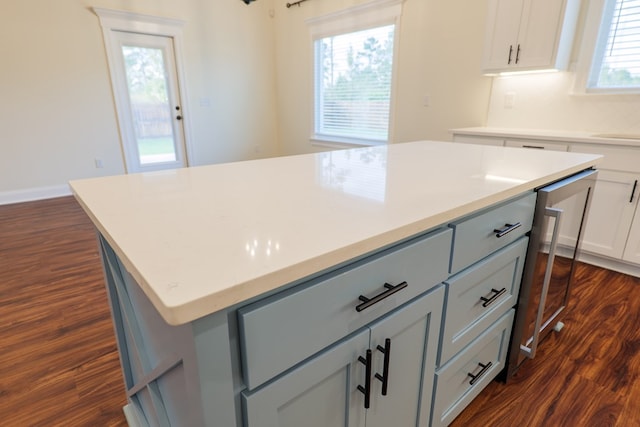 kitchen with gray cabinetry, a center island, light countertops, decorative backsplash, and dark wood finished floors