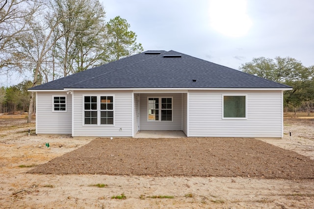 back of property with a patio and roof with shingles