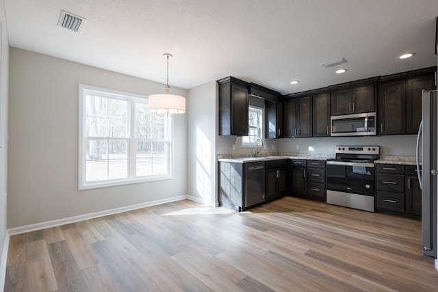 kitchen with light wood finished floors, visible vents, appliances with stainless steel finishes, a textured ceiling, and a sink