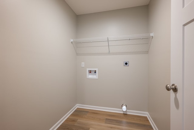 clothes washing area featuring hookup for a washing machine, electric dryer hookup, wood finished floors, laundry area, and baseboards